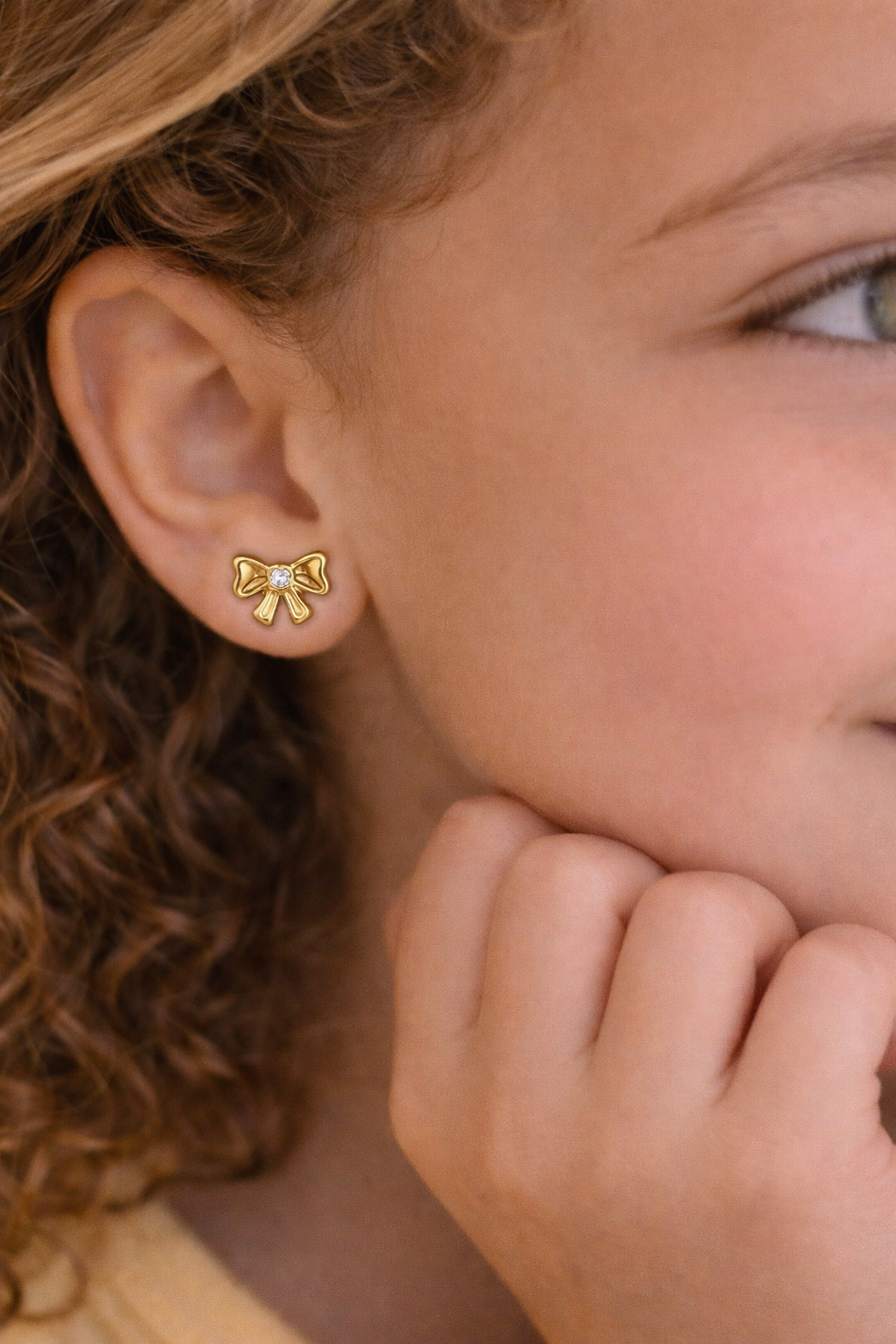 Delicate hypoallergenic children's earring in a bow shape, 18k gold plated.